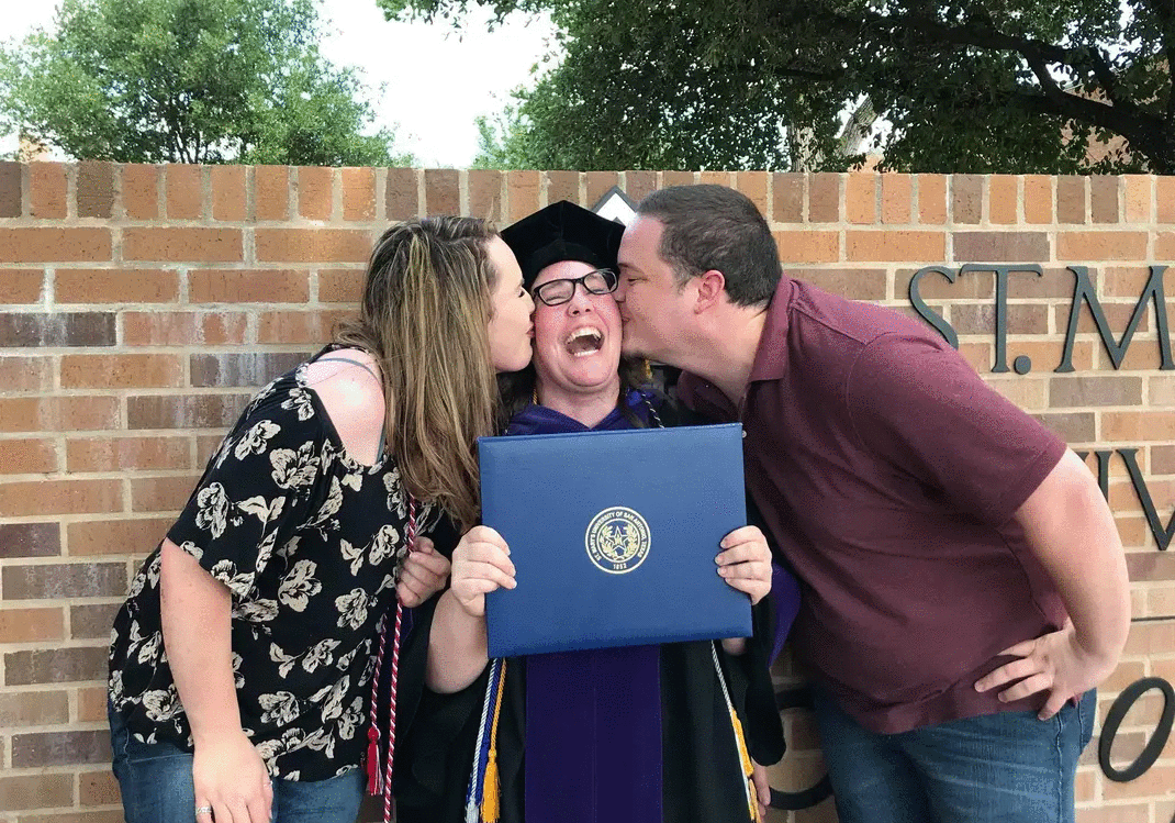 Graduate holding diploma being kissed